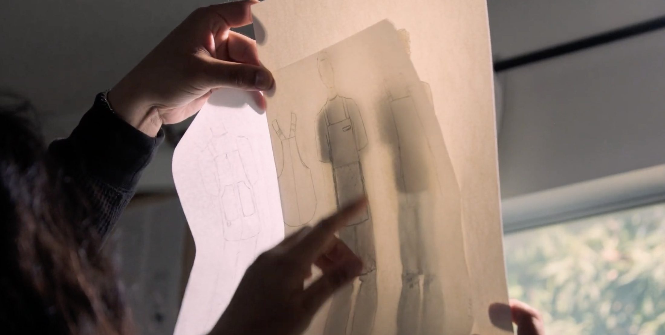 Hands holding apron sketches up to the light